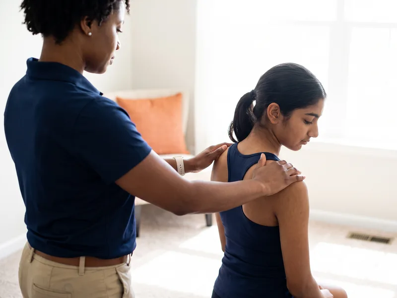 Therapist performing a hands-on shoulder assessment on a patient