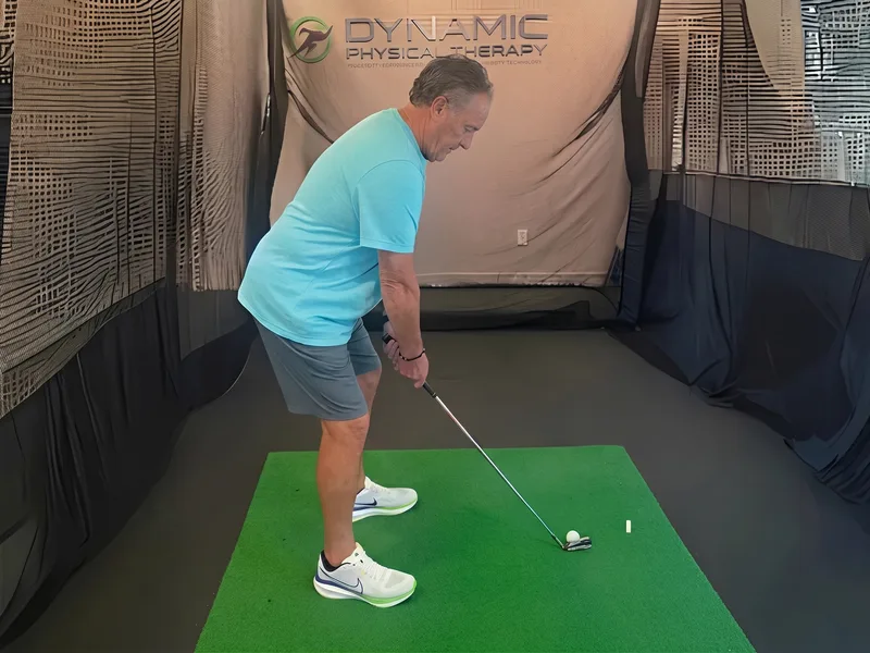 Patient in a golf swing assessment at Dynamic Physical Therapy's indoor golf bay